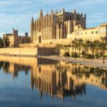 Gothic La Seu Cathedral in Palma de Mallorca reflects in a tranquil waterway.